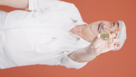 Vertical-video-of-Old-man-holding-bitcoin-and-showing-it.